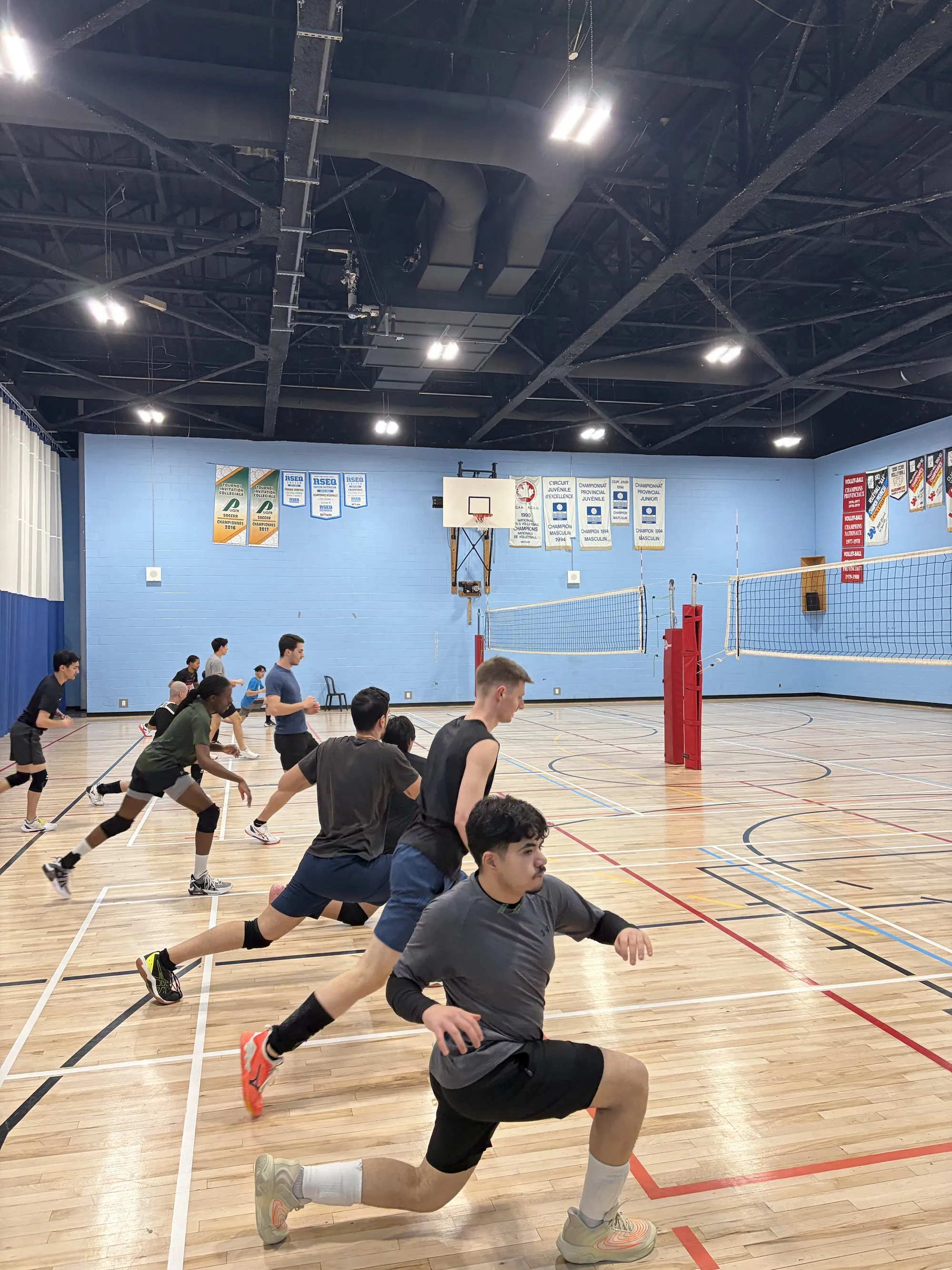 Athlètes à l'entraînement dans un gymnase comptant deux terrains de volleyball